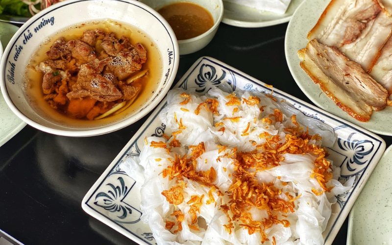 Assiette de bánh cuốn Phủ Lý à Hà Nam, fines crêpes de riz garnies d’oignons frits croustillants, servies avec porc grillé, poitrine de porc tranchée et bol de sauce nuoc-mâm parfumée