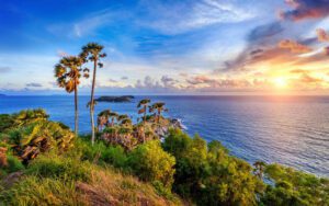 Vue panoramique du cap Promthep au coucher du soleil, avec des palmiers et l'océan scintillant à l'horizon
