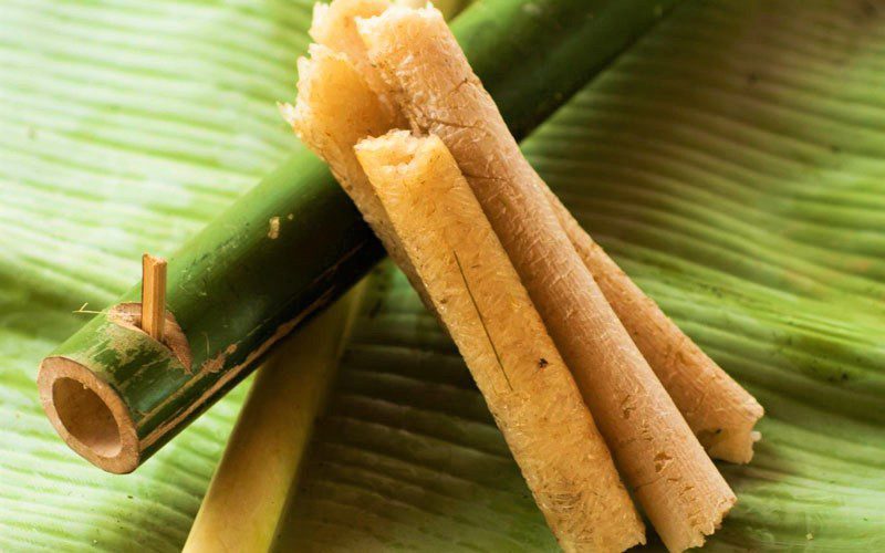 Riz gluant cuit dans des tubes de bambou (cơm lam), spécialité vietnamienne traditionnelle, présenté sur une feuille verte