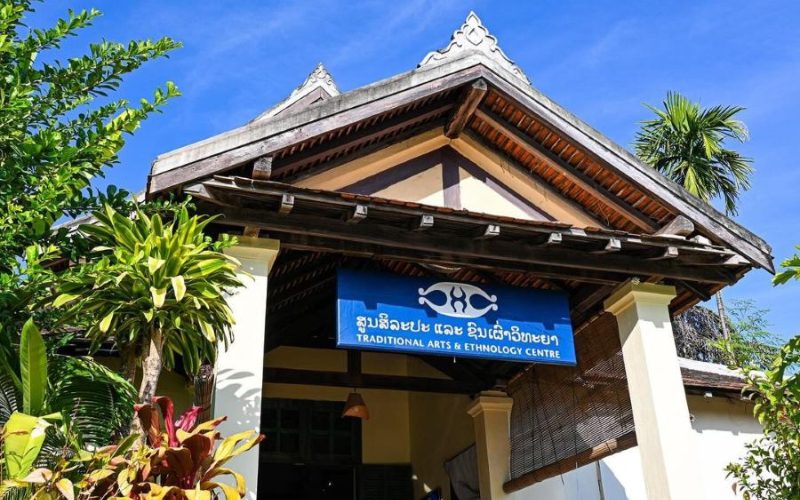 Façade du Centre des Arts Traditionnels et d'Ethnologie à Luang Prabang, entourée de verdure, avec son enseigne bleue caractéristique
