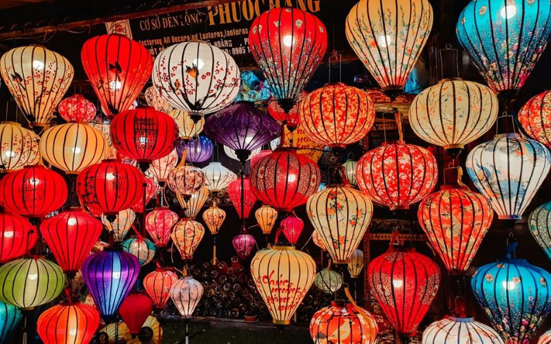 Ensemble de lanternes vietnamiennes traditionnelles colorées suspendues dans une rue de Hoi An, créant une ambiance chaleureuse et festive lors du festival des lanternes