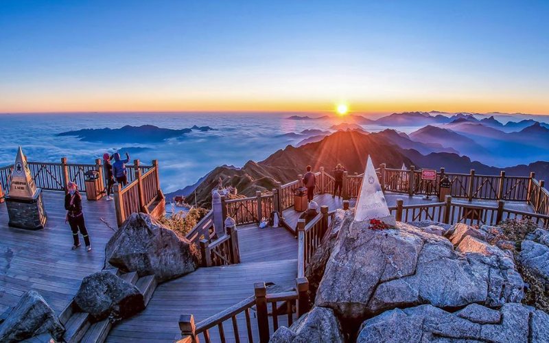 Plateforme d’observation au sommet du Fansipan, le toit de l’Indochine, où des visiteurs admirent le lever du soleil au-dessus d’une mer de nuages et des chaînes de montagnes majestueuses