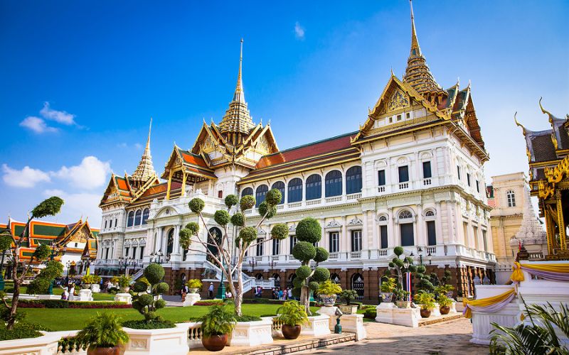 Vue du majestueux Grand Palais à Bangkok, mettant en valeur son architecture thaïlandaise élégante, ses toits dorés et ses jardins soigneusement entretenus