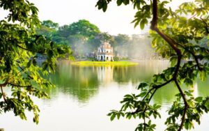 Vue pittoresque sur la tour de la Tortue (Tháp Rùa) située au centre du lac Hoàn Kiếm à Hanoï, Vietnam, encadrée par des branches feuillues et baignée par une douce lumière matinale