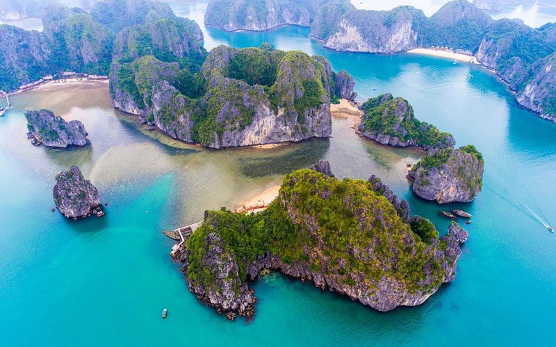 Vue aérienne spectaculaire des îlots rocheux et plages de sable doré dans la baie de Lan Ha, avec une mer turquoise paisible entourant le paysage