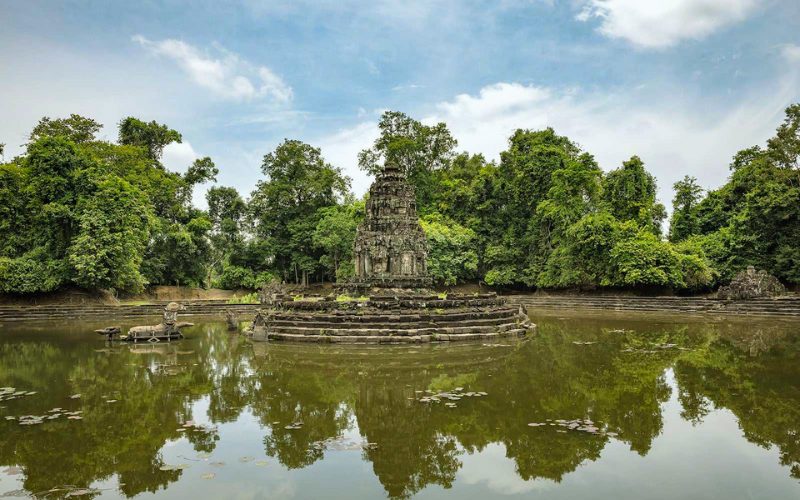 Temple de Neak Pean au Cambodge, situé sur une île circulaire au centre d’un bassin entouré de jungle luxuriante, avec un reflet paisible sur l’eau