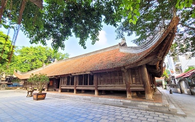 Maison communale de Đình Bảng à Bắc Ninh, imposant édifice en bois traditionnel avec un toit de tuiles recourbé, soutenu par de solides colonnes, entouré d’une vaste cour pavée et d’arbres anciens