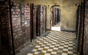 Cellules de détention en briques au Musée du Génocide de Tuol Sleng à Phnom Penh, avec un sol en carreaux blancs et marron et des murs marqués par le temps