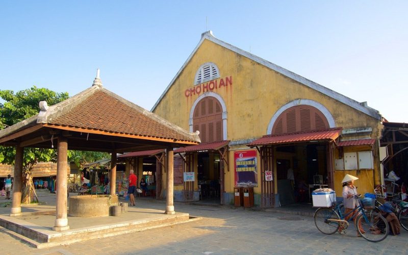 Façade du marché de Hoi An, un bâtiment jaune emblématique de la vieille ville, où les habitants et visiteurs viennent acheter des produits locaux