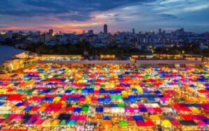 Vue aérienne du marché Chatuchak à Bangkok au crépuscule, avec ses innombrables stands aux toits colorés