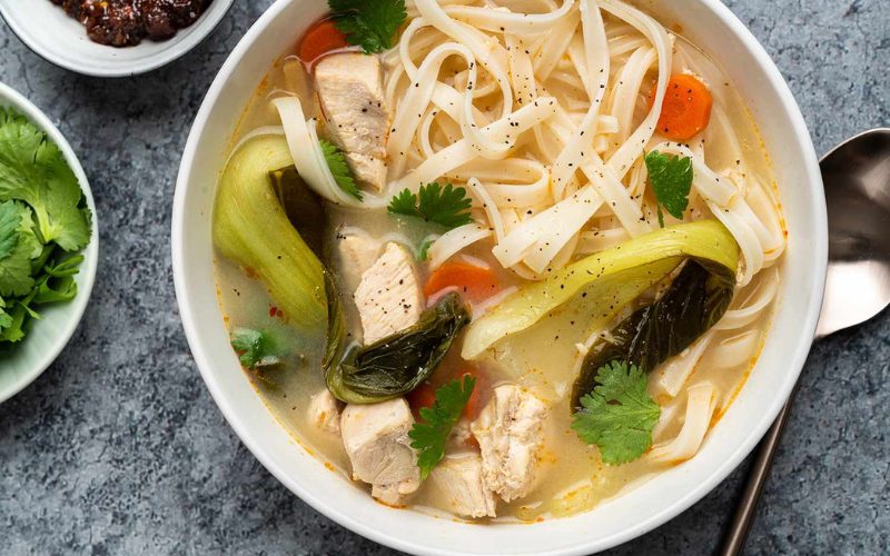 Bole de nouilles en soupe avec les morceaux de poulet, des légumes frais comme le bok choy et les carottes