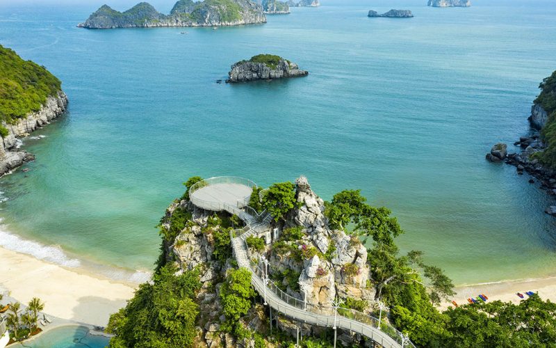 Plateforme d’observation panoramique sur un promontoire rocheux de l’île de Cat Ba, surplombant une plage de sable blanc et une mer turquoise parsemée d’îlots