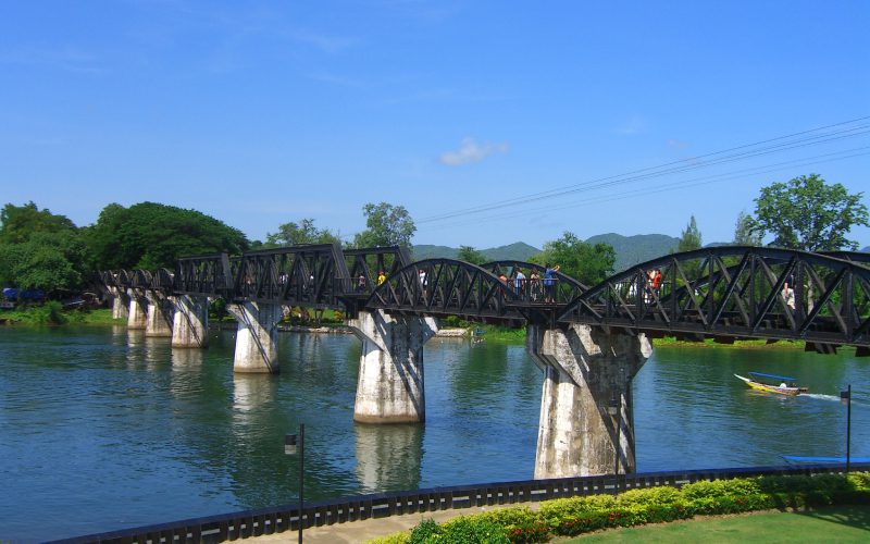 Vue du célèbre Pont sur la rivière Kwai à Kanchanaburi, Thaïlande, avec sa structure en acier emblématique, enjambant la rivière sous un ciel bleu