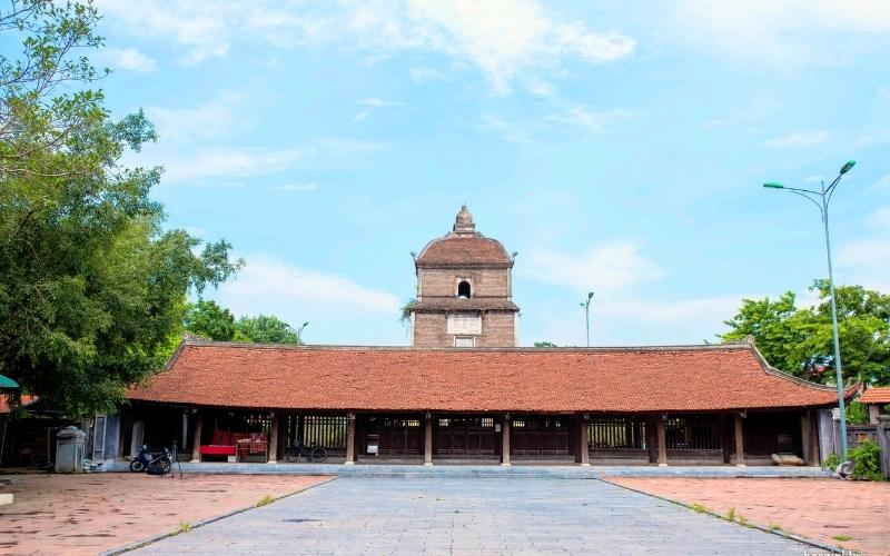 Pagode de Vĩnh Nghiêm à Bắc Giang, édifice bouddhique ancien avec un toit de tuiles rouges et une grande cour pavée, dominé par une tour en briques se dressant à l’arrière-plan