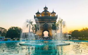 Fontaine devant le monument de Patuxay à Vientiane, au coucher du soleil, avec l'arc imposant en arrière-plan