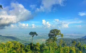 Vue panoramique sur les Hautes Terres de Bokor, Cambodge, avec une végétation luxuriante, des montagnes verdoyantes et un ciel bleu parsemé de nuages