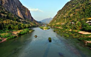 Vue panoramique d’une rivière sinueuse entourée de hautes montagnes verdoyantes et de villages nichés dans la végétation