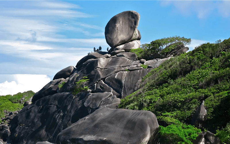 L'image montre un paysage naturel avec des formations rocheuses massives et des arbres verts.
