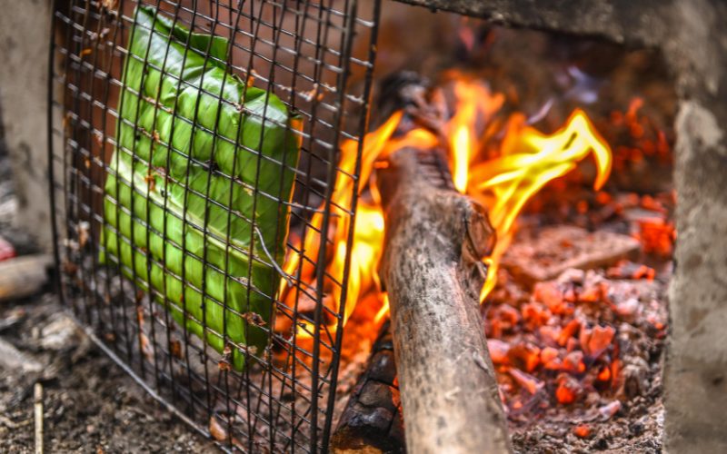 Rêu đá enveloppé de feuilles de bananier, grillé sur un feu de bois, dégageant une atmosphère traditionnelle et rustique de cuisine vietnamienne