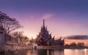 Vue du Sanctuaire de la Vérité à Pattaya au coucher du soleil, mettant en valeur son architecture en bois sculpté détaillée