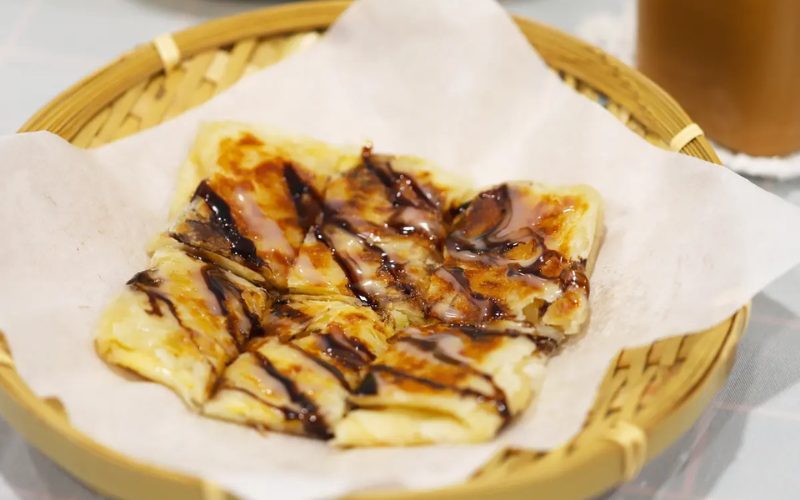Crêpe thaïlandaise croustillante découpée en morceaux, servie sur du papier sulfurisé dans un panier en bambou
