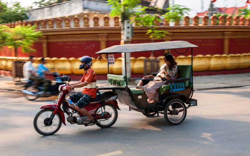 Tuk-tuk transportant une passagère dans une rue animée du Cambodge
