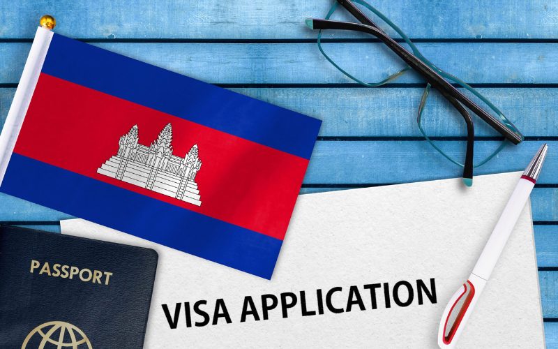 Image représentant une demande de visa pour le Cambodge, avec le drapeau cambodgien, un passeport, et une feuille avec l'inscription 'Visa Application'