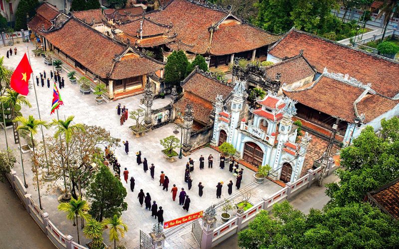 Vue aérienne du village ancien de Hung Lo à Phu Tho, avec ses maisons traditionnelles aux toits de tuiles rouges et une procession culturelle dans la cour centrale