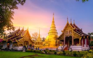 Vue du temple Wat Phra Singh à Chiang Mai, Thaïlande, illuminé par la lumière dorée du coucher de soleil, mettant en valeur son architecture traditionnelle et son stupa doré scintillant