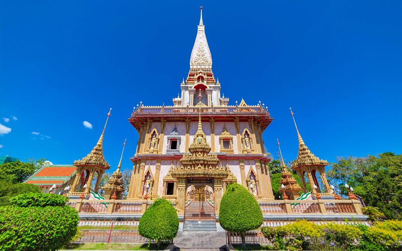 Le temple Wat Chalong à Phuket, un sanctuaire bouddhiste majestueux avec ses détails dorés, ses façades richement décorées et un ciel bleu éclatant en arrière-plan